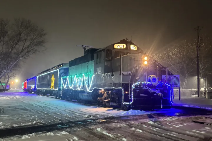 Train illuminated with festive lights on a snowy night.
