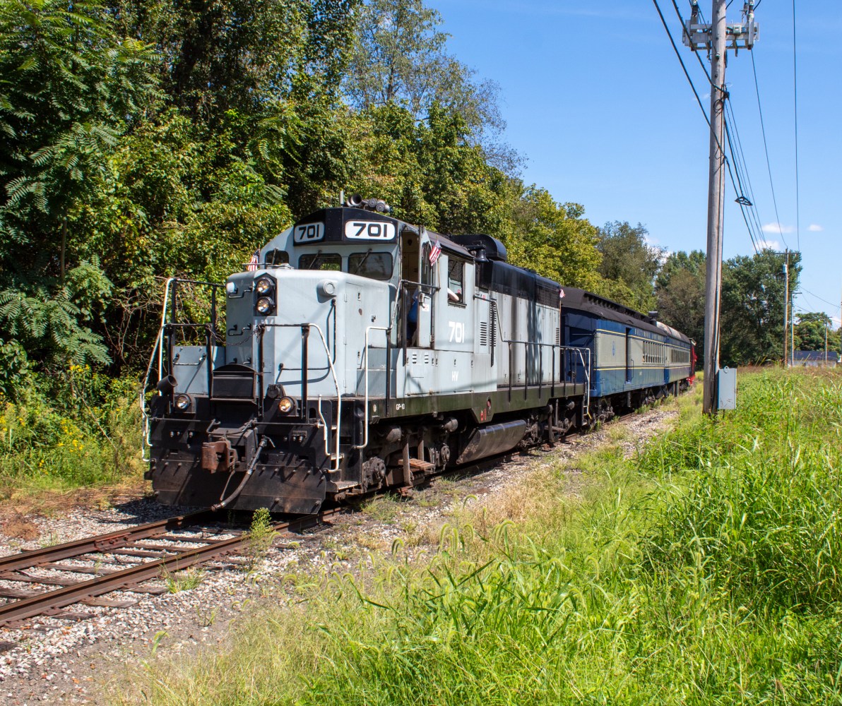 A blue locomotive with number 701 on tracks near trees.