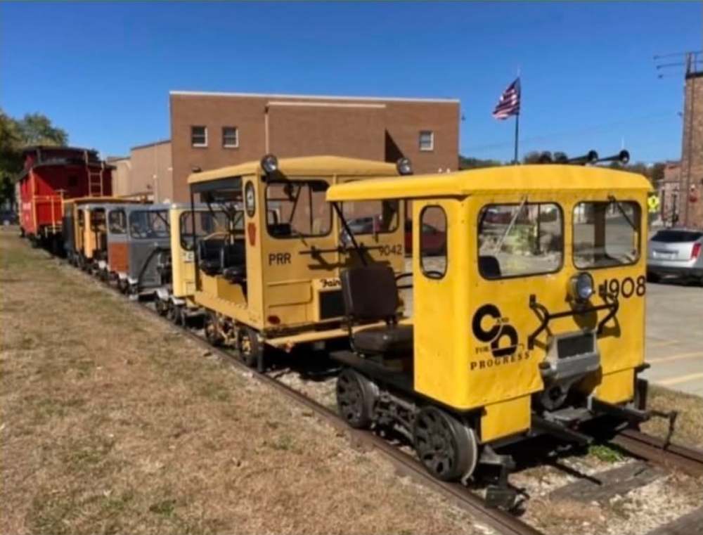 Small yellow maintenance rail vehicles lined up on train tracks.